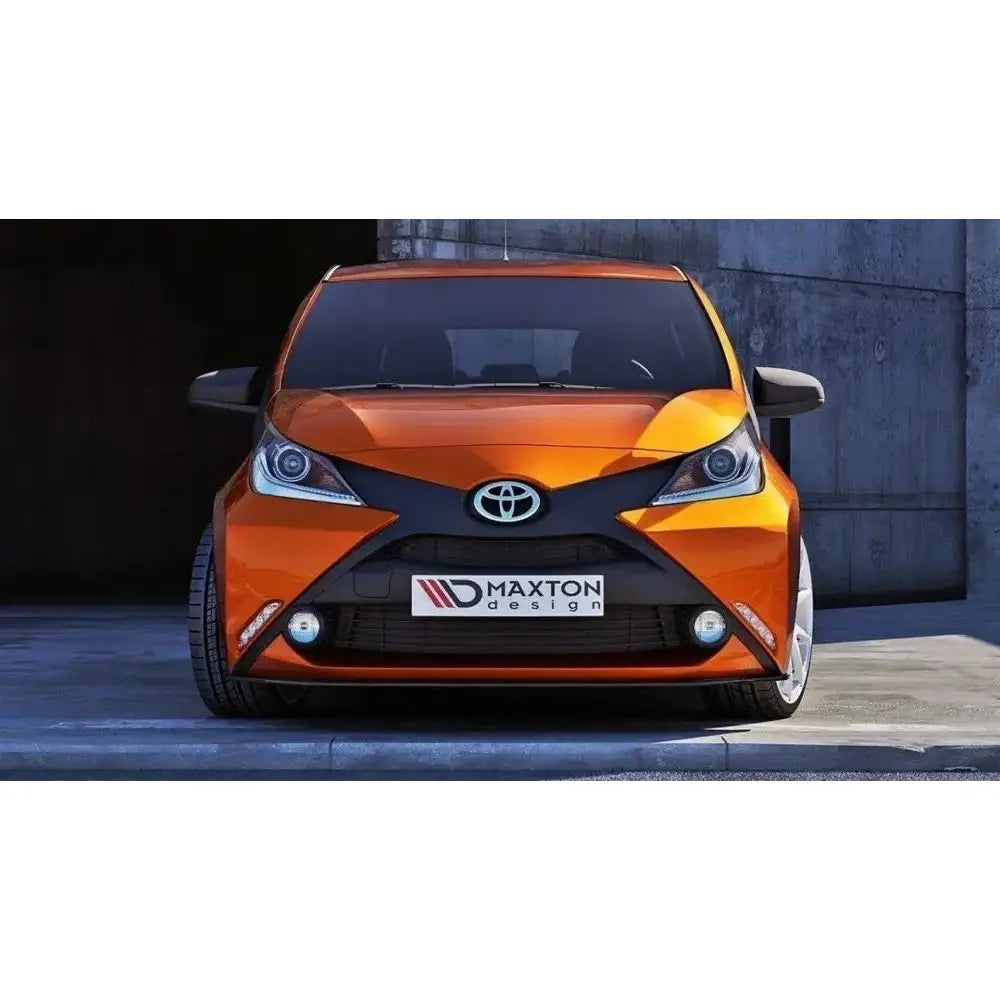 Spoiler til Toyota Aygo Mk2, oransje bil forfra med svarte detaljer og Maxton Design-logo på skiltet.