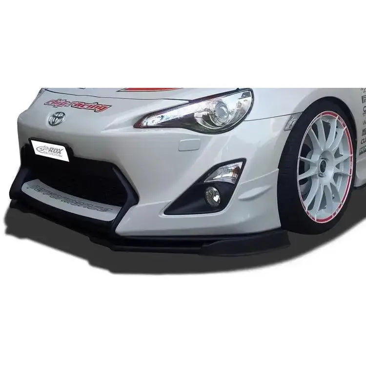 Frontspoiler på Toyota GT86 Aero, hvit sportsbil med sorte detaljer og hvite felger sett skrått forfra.