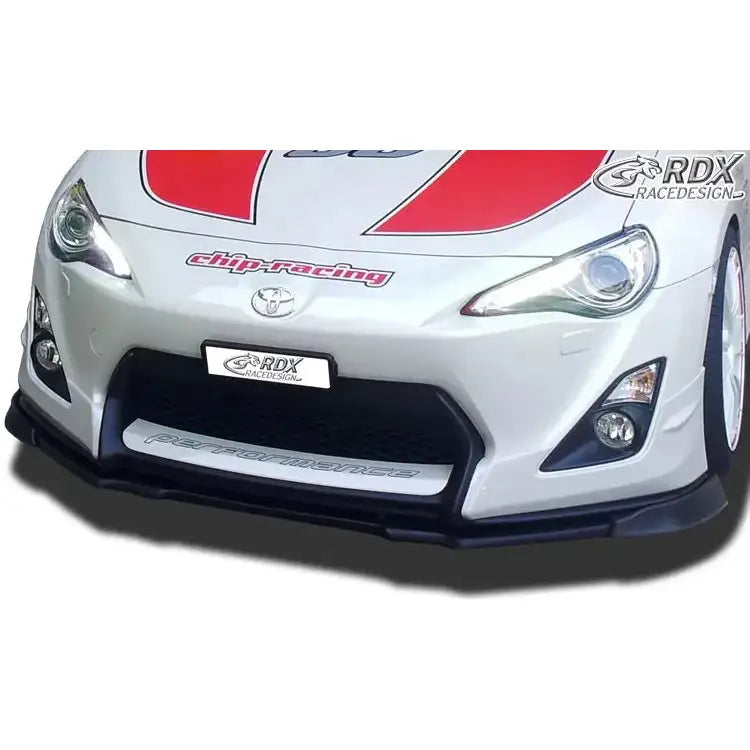 Front lip på Toyota GT86 Aero, sort spoiler montert foran på hvit bil med røde dekaler og logo.