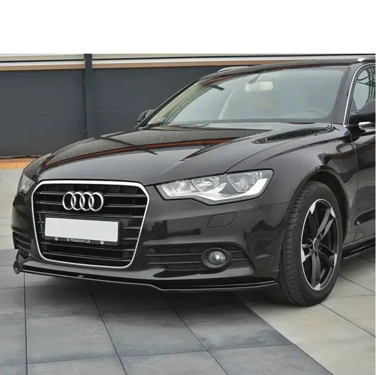 Spoiler Audi A6 C7 V.1 montert på sort bil med svarte felger og krom frontgrill, sett forfra fra venstre.