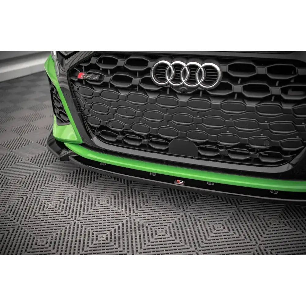 Front lip på Audi RS3 8Y med grønn spoiler, sort grill og sølvfargede ringer sett fra lav vinkel.