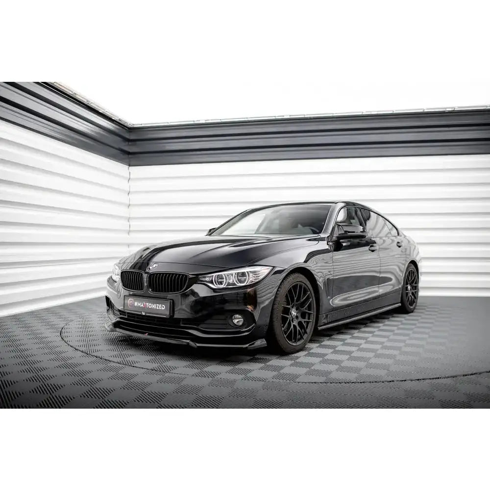 Frontleppe på BMW 4 Gran Coupe F36 V.1 i svart lakk med sorte felger på sjakkrutet gulv.