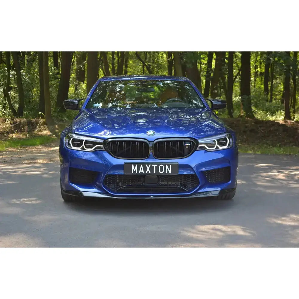 Spoiler til BMW M5 F90 V.1 montert på blå bil sett forfra med svarte grilldetaljer og Maxton-skilt.