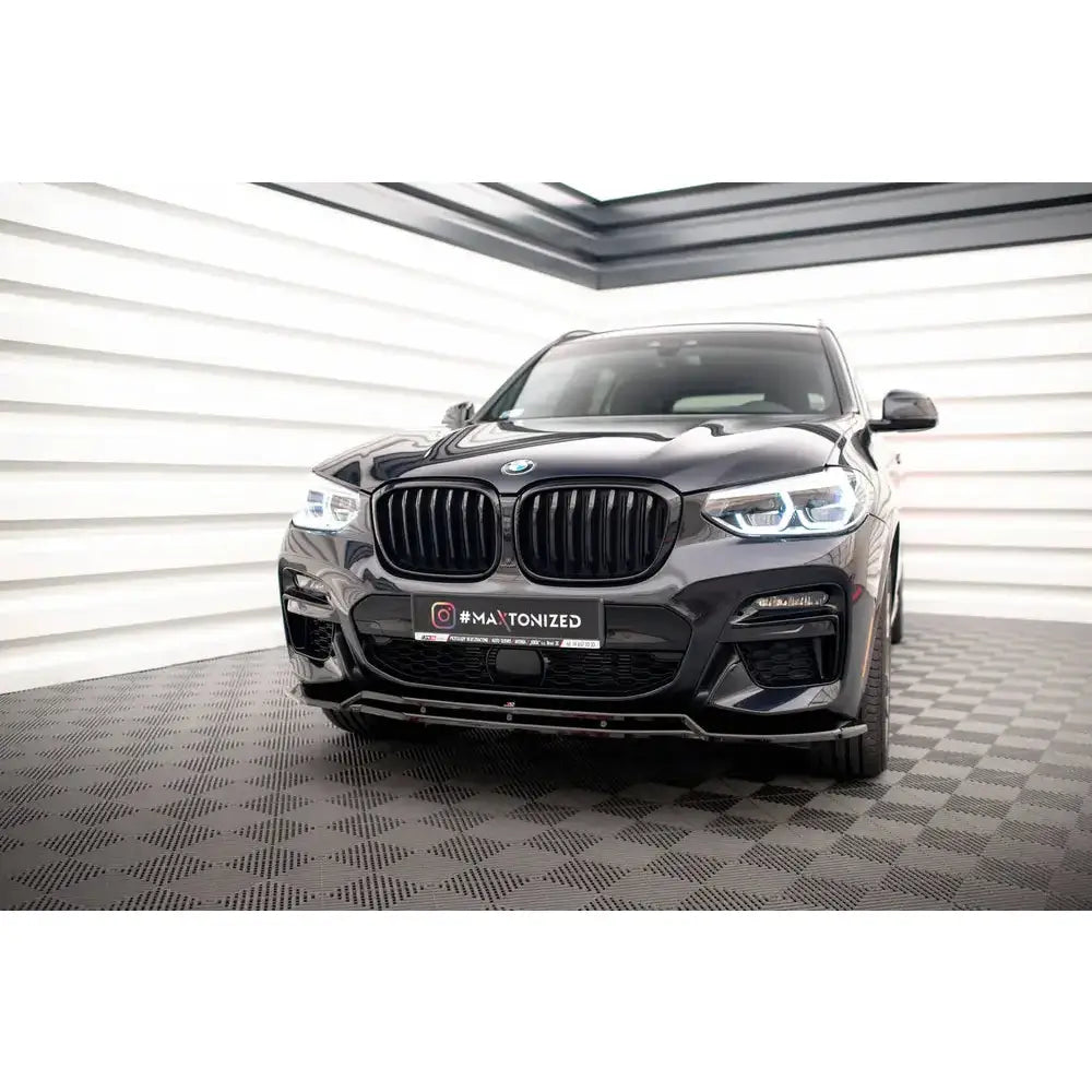 Front splitter på BMW X3 G01 V.1 M-Pack med sorte grilldetaljer og LED-lykter, sett forfra innendørs.