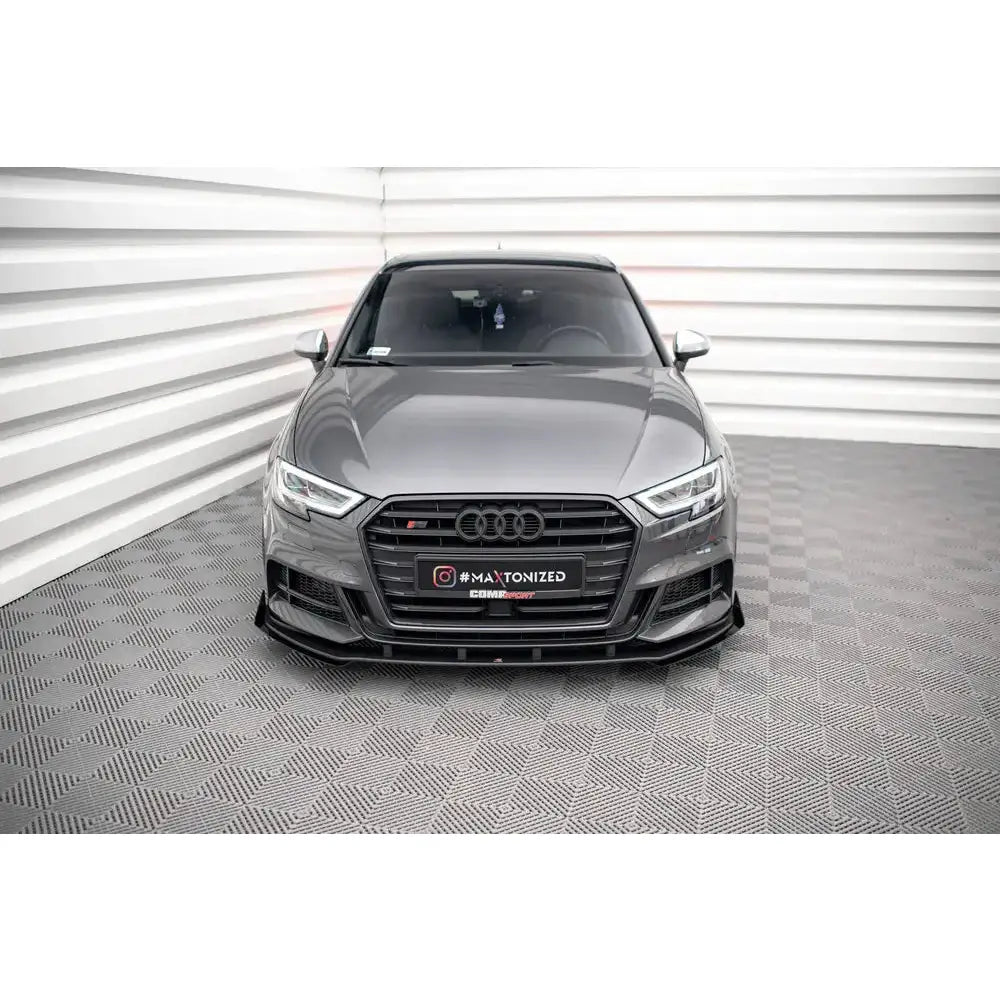 Frontspoiler på Audi S3 Sportback 8V Facelift med svarte flaps, sett rett forfra mot lyse vegger.