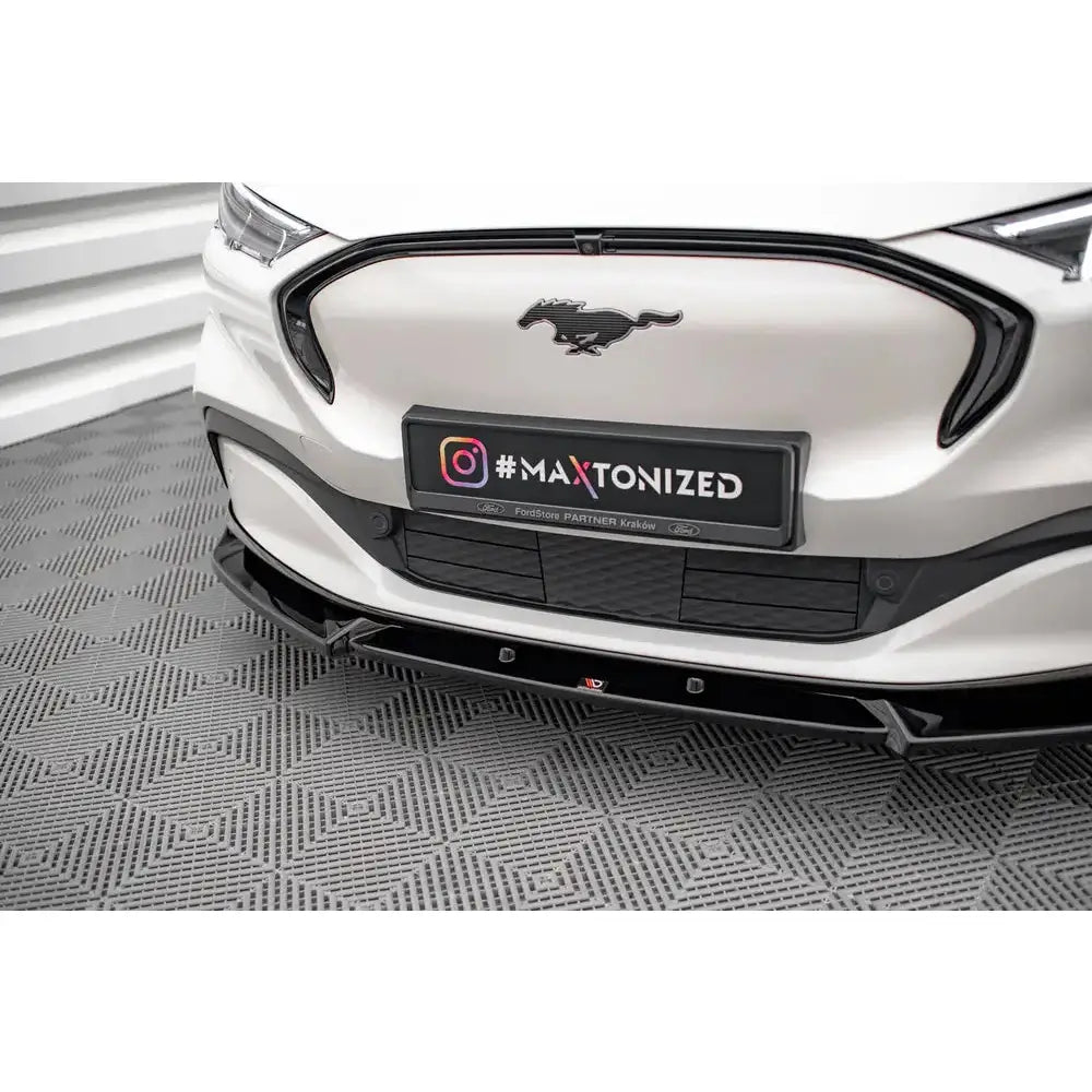 Spoiler til Ford Mustang Mach-E Mk1 V.1 i blank svart finish montert på hvit bil, sett forfra.