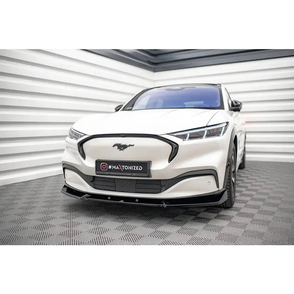 Front splitter på Ford Mustang Mach-E Mk1 V.1 med svarte detaljer, sett forfra på rutete gulv.