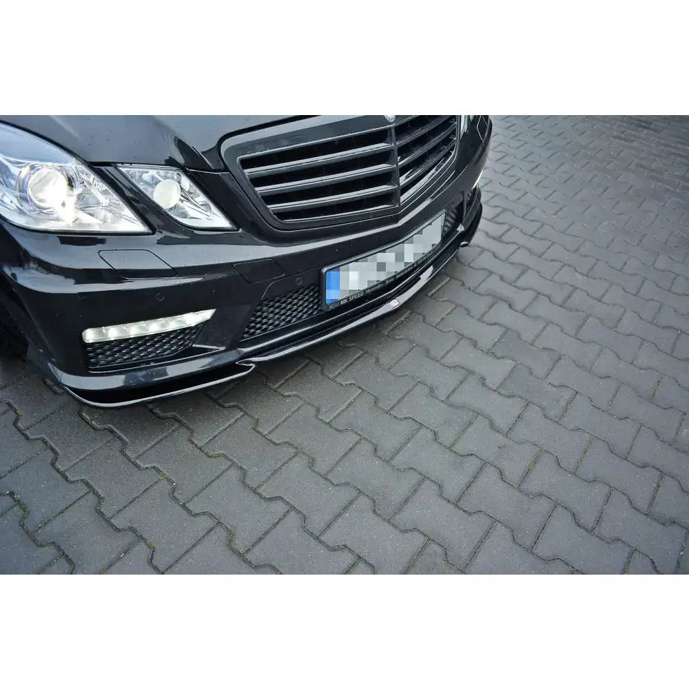 Front splitter på Mercedes E63 AMG W212 med glanset sort plast, synlig LED-lys og grill, skrå forfra.