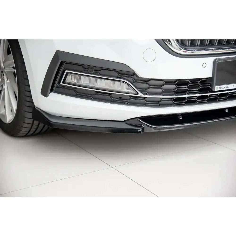 Front lip på Skoda Octavia MK4 V.1 med sort spoiler, grilldetaljer og synlige LED-lys på hvit bil.