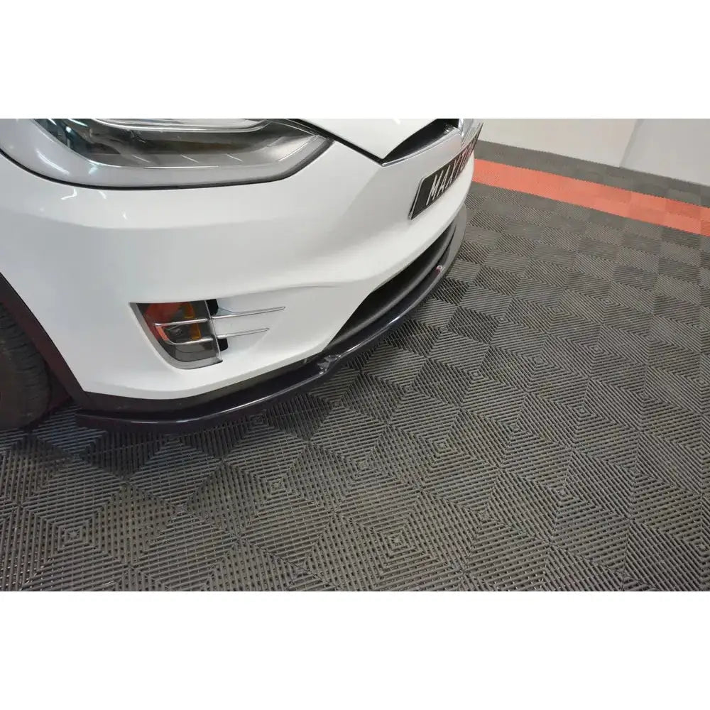 Front splitter på Tesla Model X V.1, sort detalj foran tåkelys, nærbilde på grått rutete gulv.