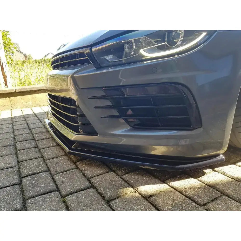 Spoiler til Volkswagen Scirocco Mk.3 R Facelift V.1 montert foran på grå bil parkert på brostein.