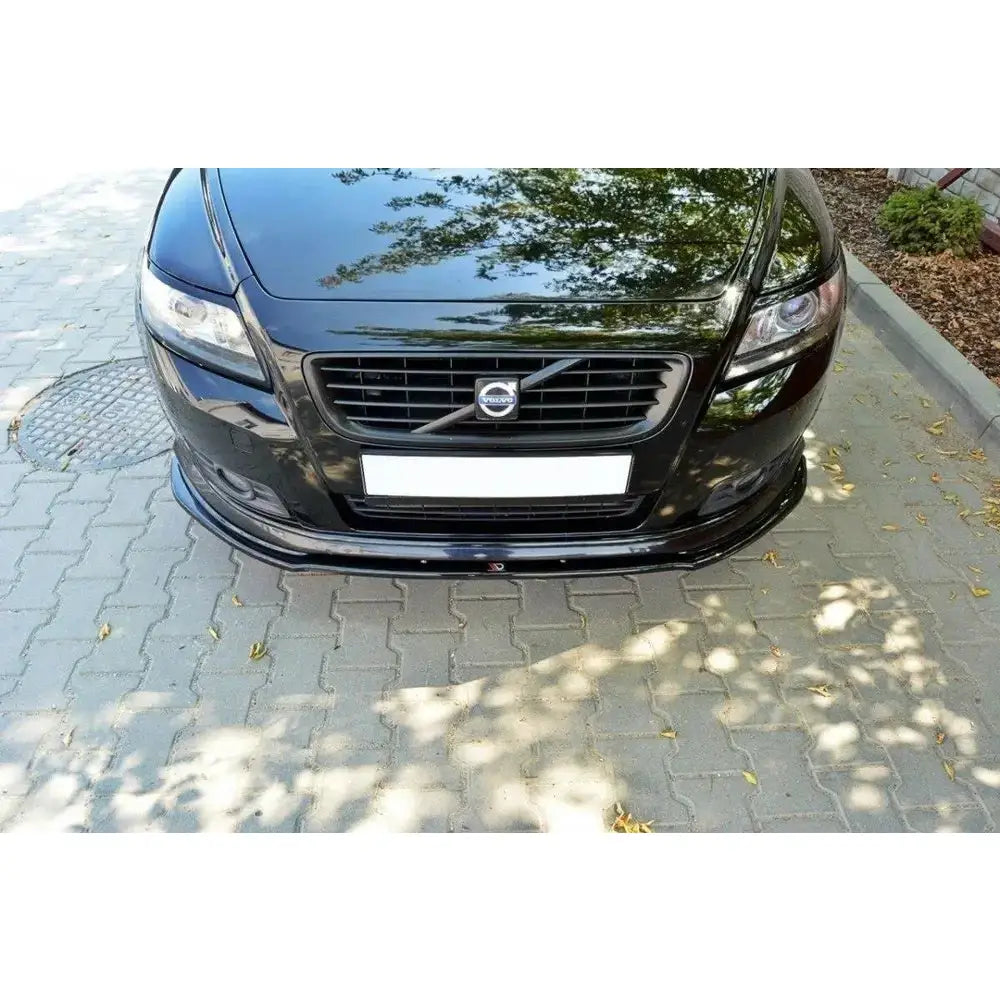 Front splitter montert på sort Volvo V50F R-Design sett forfra, parkert på steinlagt bakke.