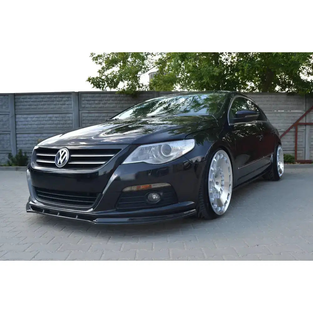 Frontspoiler på VW Passat CC med standard støtfanger, sorte detaljer og store sølvfelger sett skrått forfra.