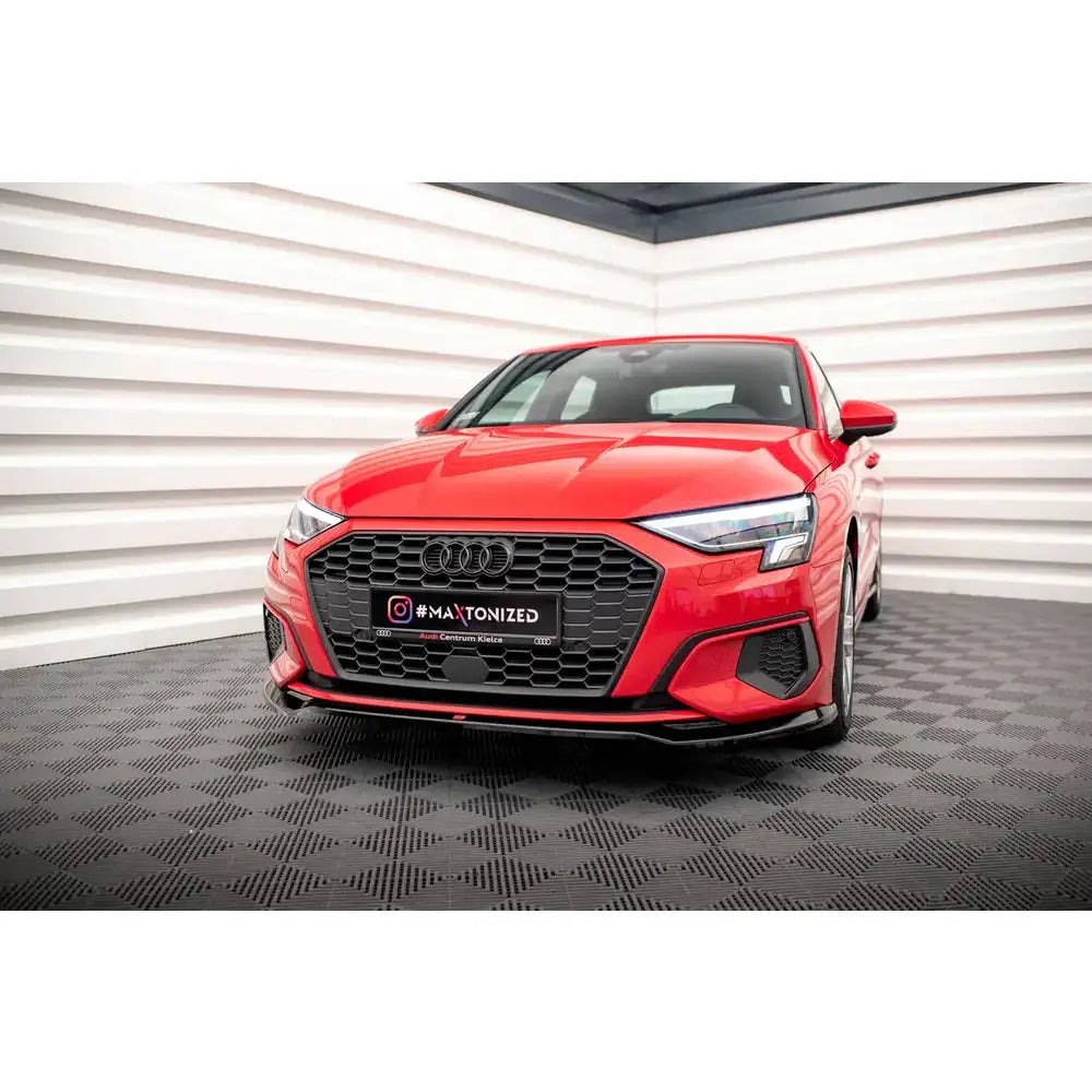 Front lip på Audi A3 8Y V.2, rød bil med sort grill og sporty detaljer, sett forfra i lyst rom.