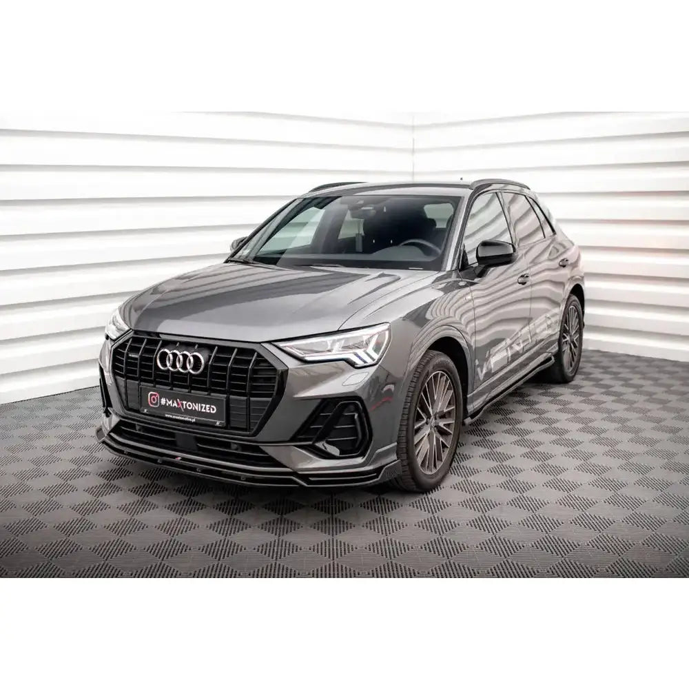 Frontspoiler på Audi Q3 S-Line V.2, grå SUV med sorte detaljer og store felger innendørs.