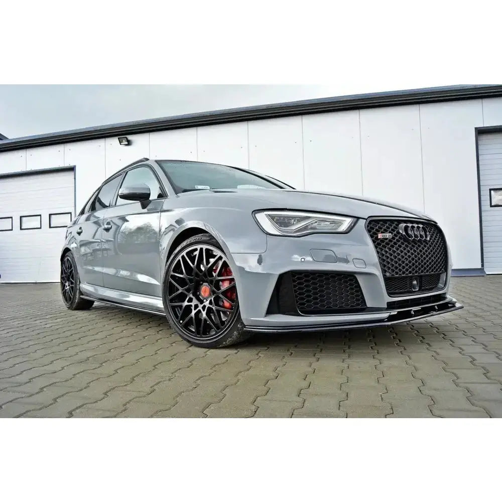 Frontspoiler på Audi RS3 8V Sportback med sorte felger og røde bremsekalipere parkert foran bygning.
