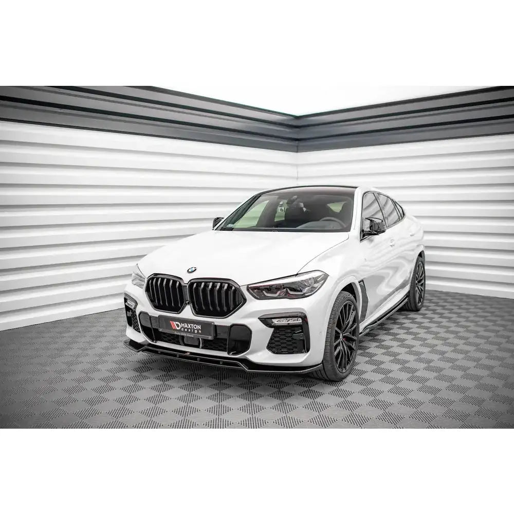 Front splitter på BMW X6 M-Pack G06, hvit SUV med sorte detaljer og felger, innendørs.
