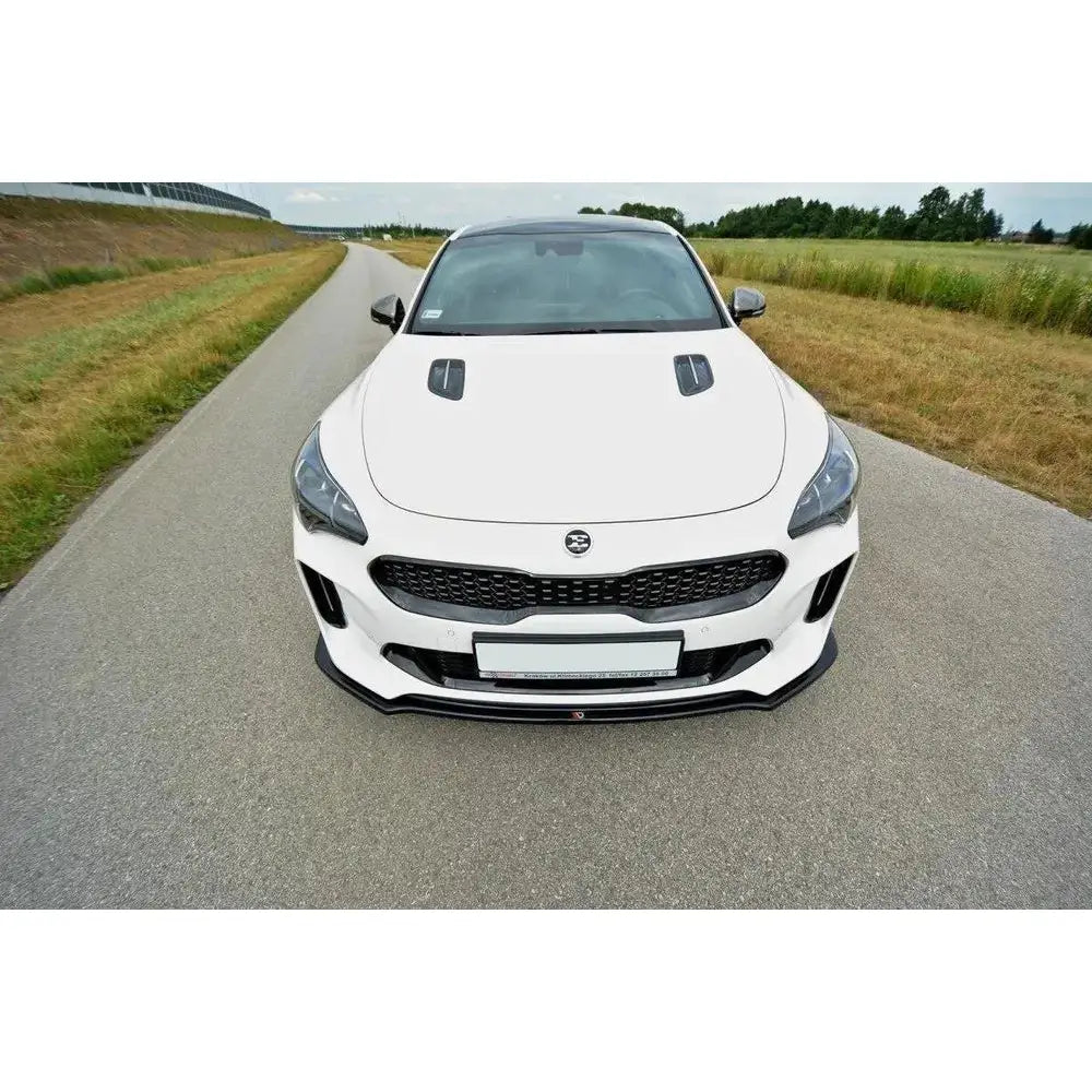 Frontspoiler Kia Stinger GT V.2 montert på hvit sportsbil med sorte luftinntak, sett forfra på vei.