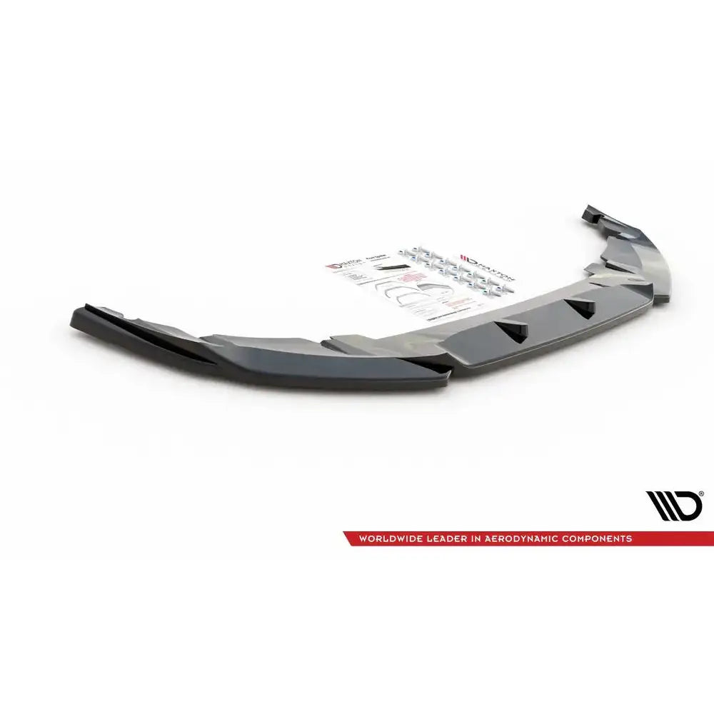 Frontspoiler Mini Countryman Mk2 F60 JCW V.2 i sort plast, skrå forfra med monteringsutstyr og instruksjonsark.