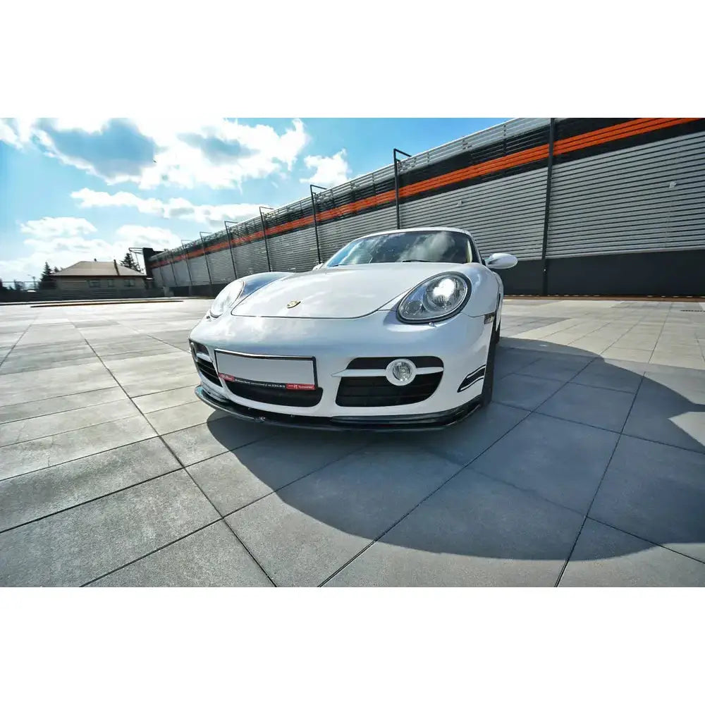 Front splitter på Porsche Cayman S 987C V.2 med sorte detaljer og LED-lykter, fotografert utendørs.