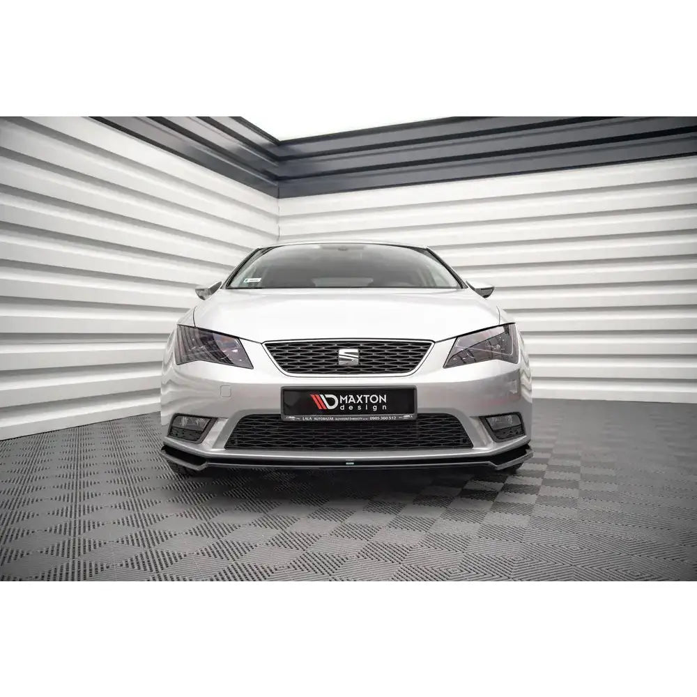 Spoiler på Seat Leon Mk3 V.2 12-16, sølvfarget bil forfra med mørk frontleppe og grill.