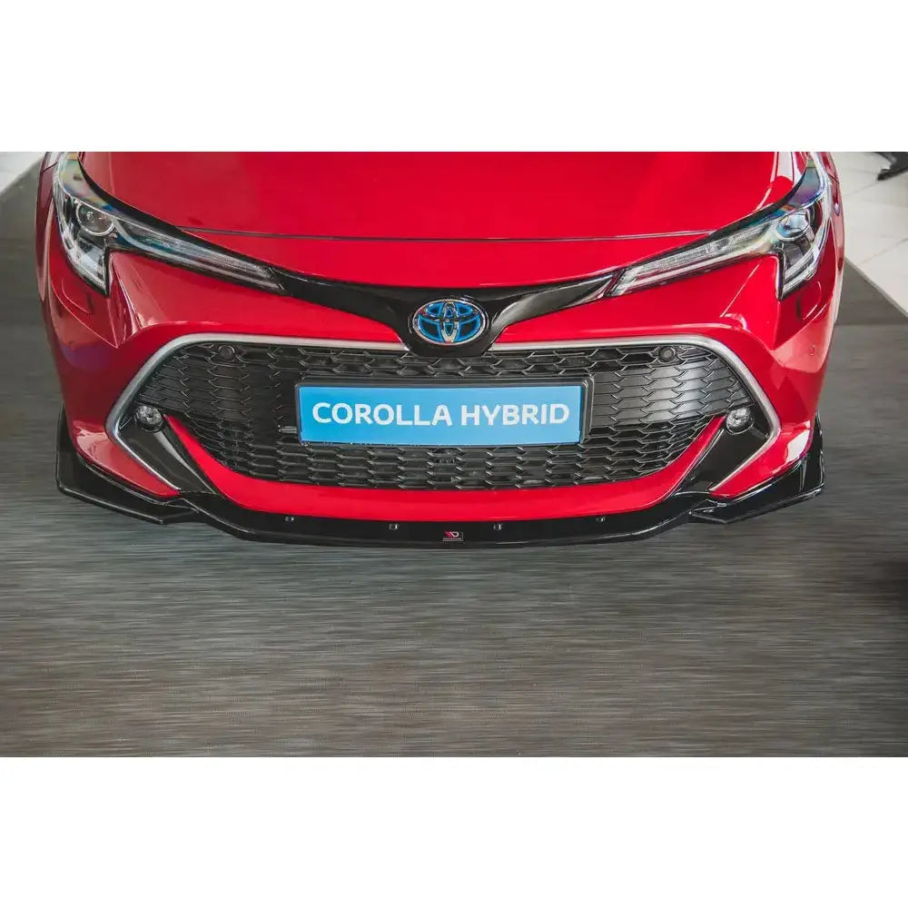 Spoiler på rød Toyota Corolla XII med sort grill, blanke detaljer og "COROLLA HYBRID" på blå nummerplate.