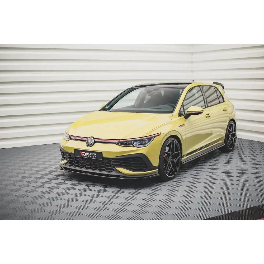 Frontspoiler på gul Volkswagen Golf 8 GTI Clubsport med sorte felger og rød stripe i grillen.