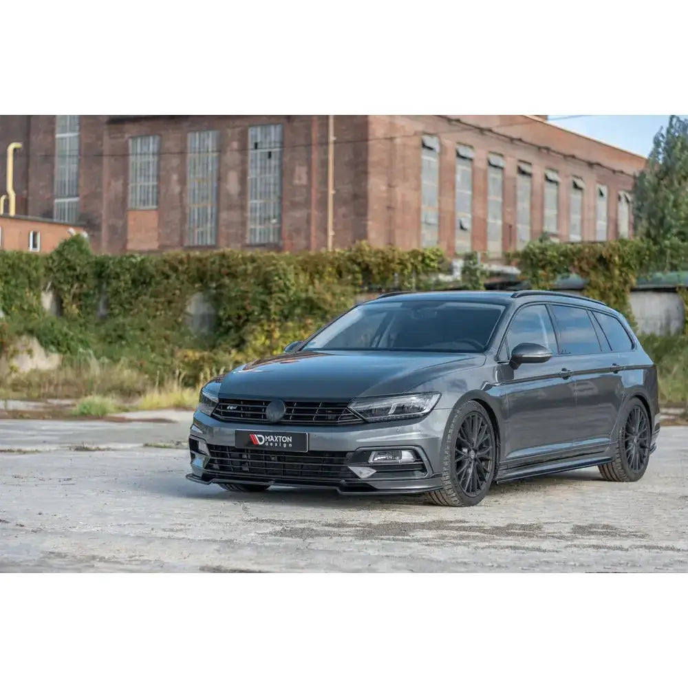 Frontleppe på Volkswagen Passat R-Line B8, mørk grå stasjonsvogn med sorte felger foran fabrikk.