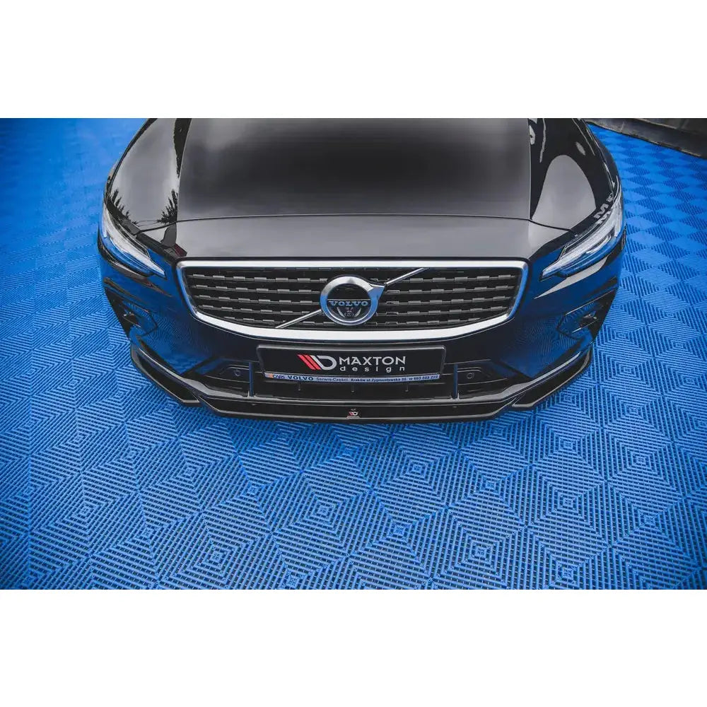 Front lip på Volvo S60 R-Design Mk3 V.2 sett ovenfra, svart bil med markert grill og logo på blått underlag.