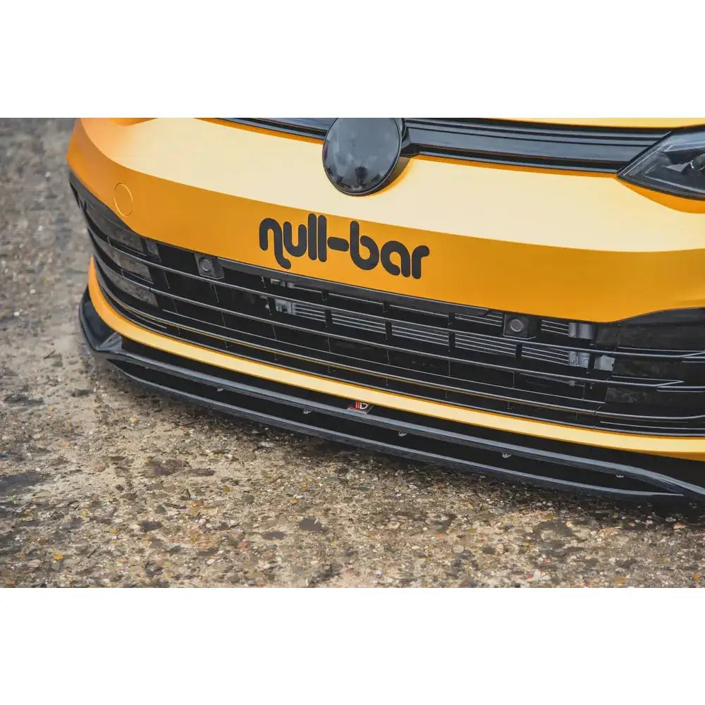Front splitter på VW Golf 8 V.2, nærbilde av gul bil med sort grill og null-bar-logo.