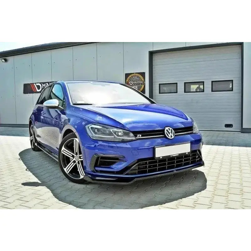 Front lip på VW Golf VII R Facelift V.2, blå bil med svarte felger foran industribygning.