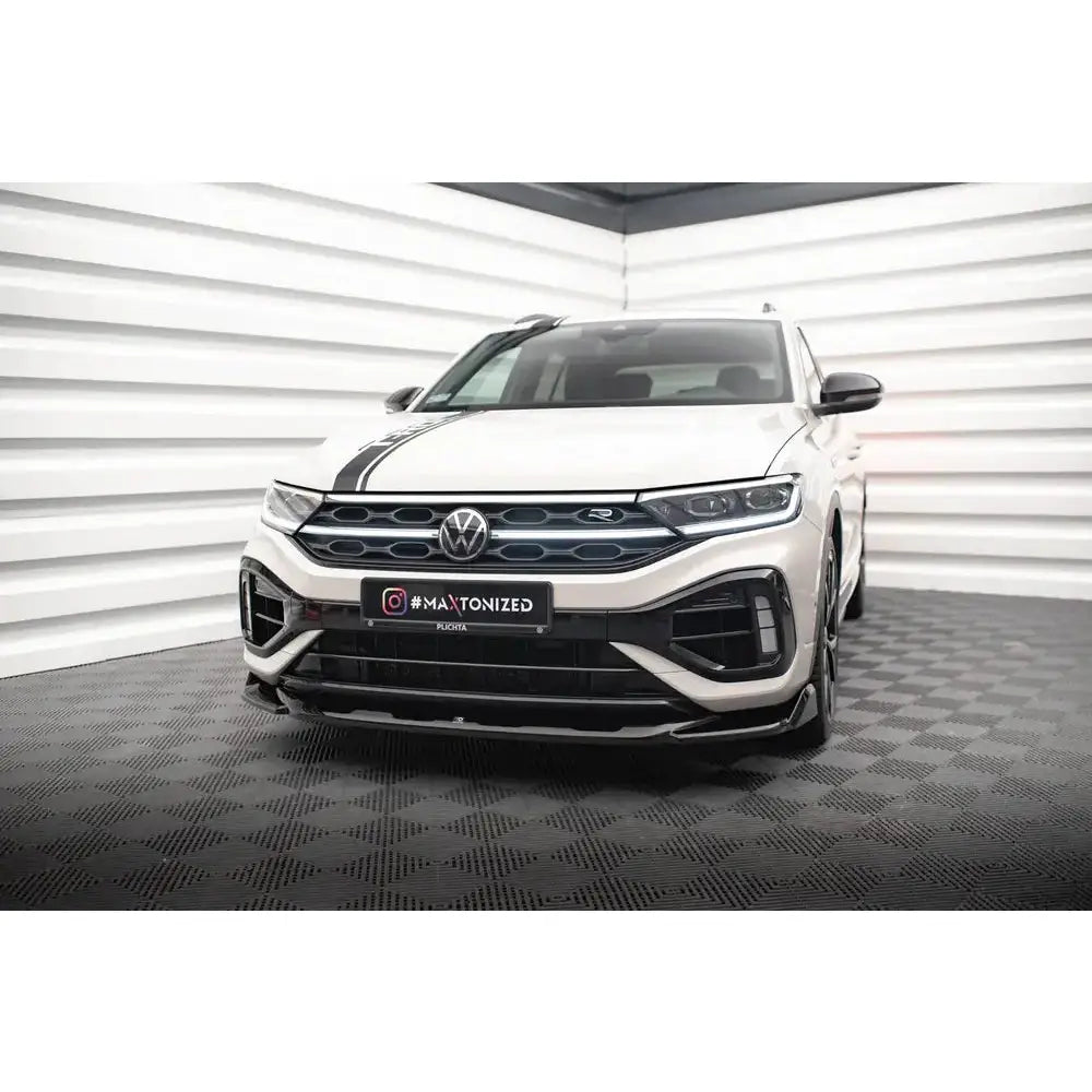 Spoiler på hvit VW T-Roc R Mk1 Facelift med sort stripe over panseret, sett forfra i lyst rom.