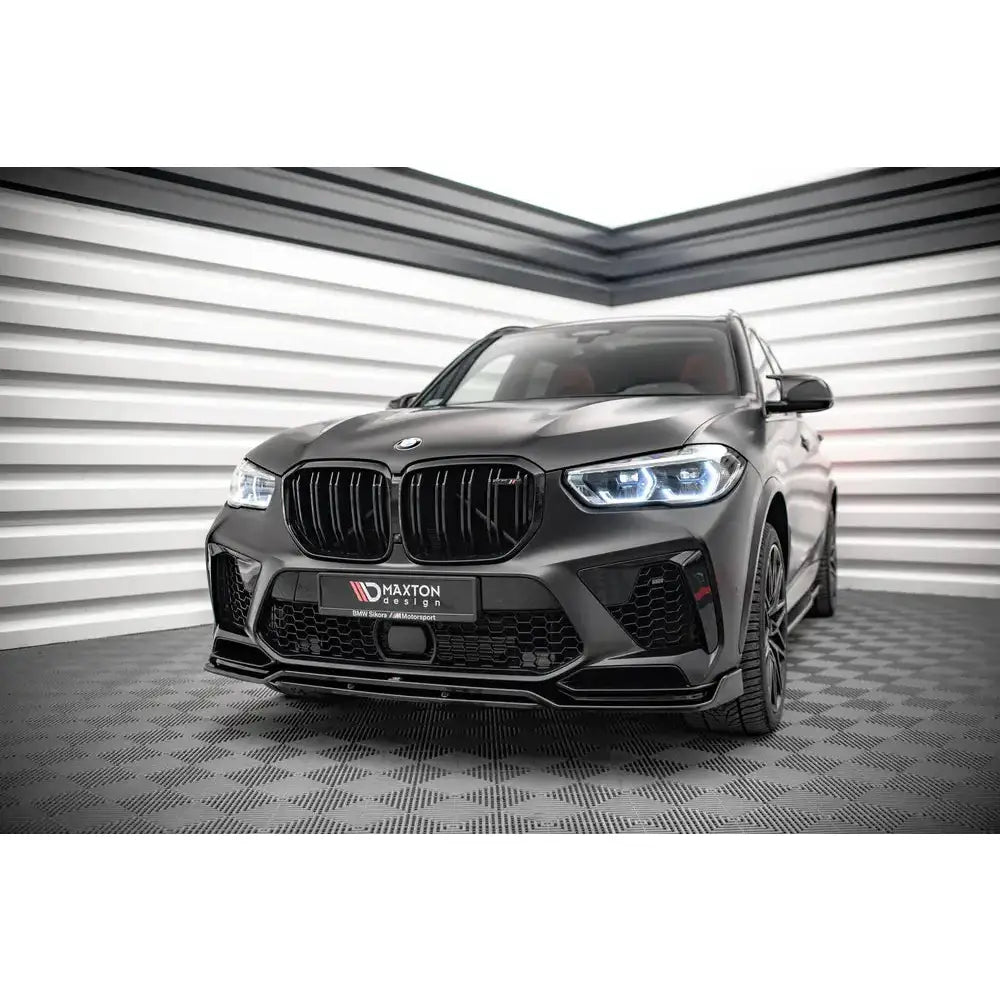 Front splitter på BMW X5M F95 med matt svart finish, synlig fra lav front-høyre vinkel innendørs.