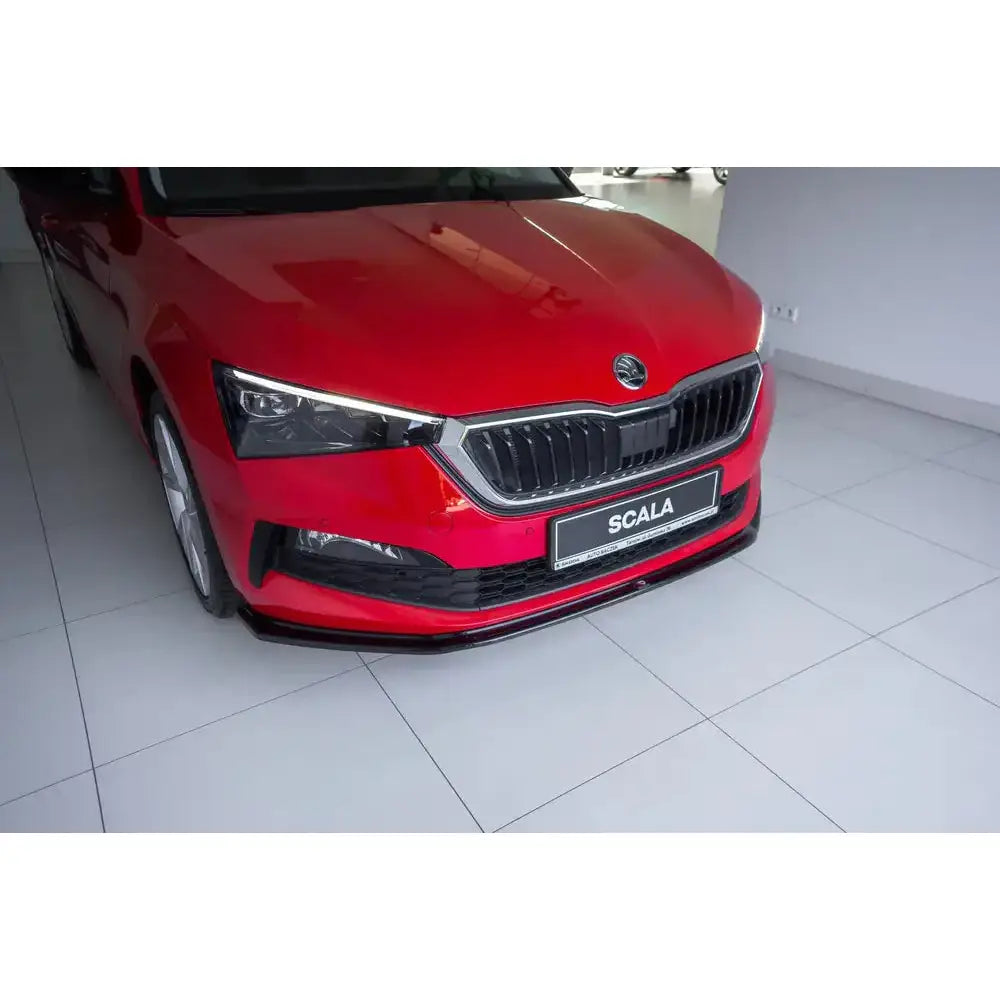 Front splitter på rød Skoda Scala V.3 med sort grill og frontleppe i lyst rom.