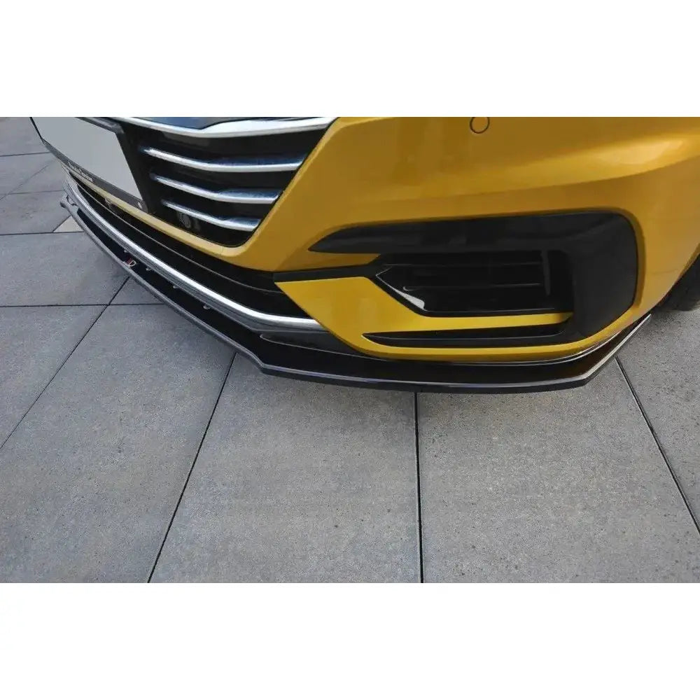 Front splitter på VW Arteon V.3, nærbilde av sort frontspoiler med kromdetaljer på gul bil.