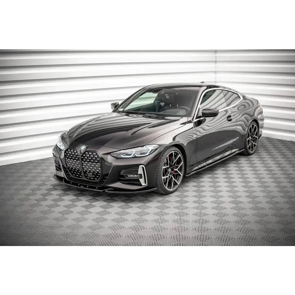 Frontleppe på BMW 4 G22 M-Pack V.4 med sorte felger, store luftinntak og bølget bakgrunn.