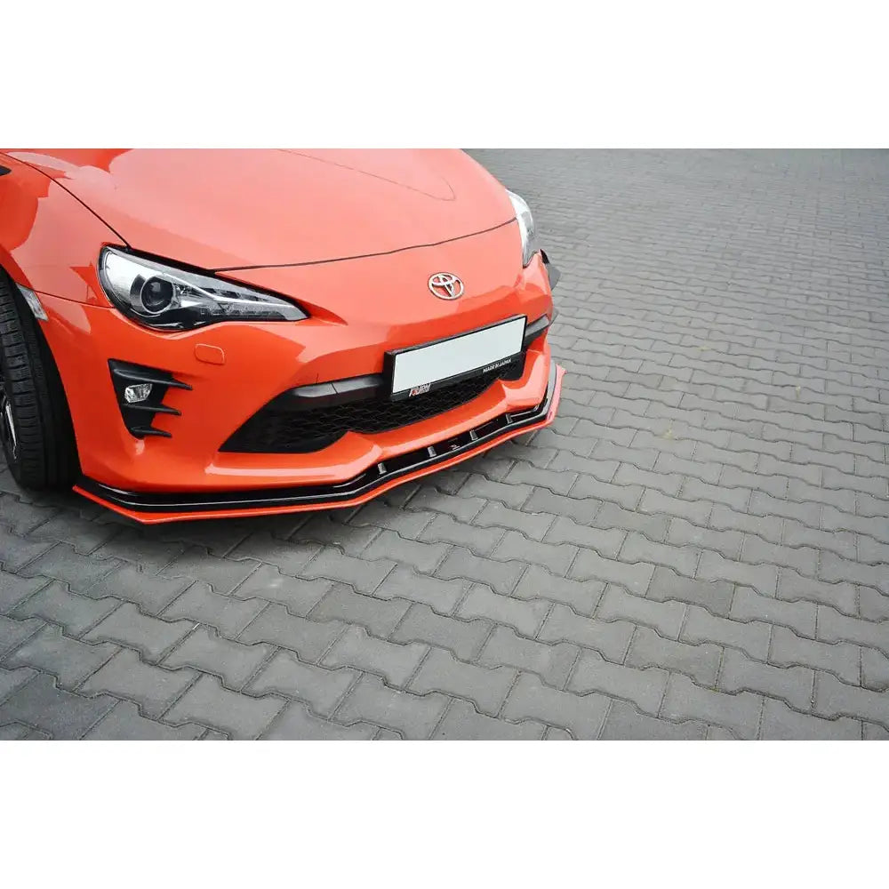 Spoiler på Toyota Gt86 Facelift V.4, oransje bil med svart frontsplitter og røde detaljer på brostein.