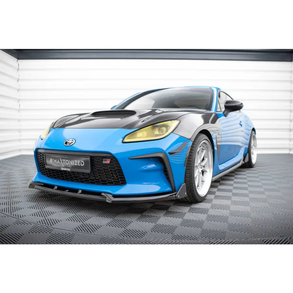 Frontleppe på Toyota GR86 Mk1 V1 med flaps, blå og svart bil sett forfra, gule lykter og sølvfelger.