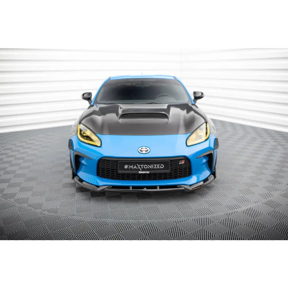 Spoiler til Toyota GR86 Mk1 V1 med flaps, blå bil med sort panser og gule frontlykter forfra.