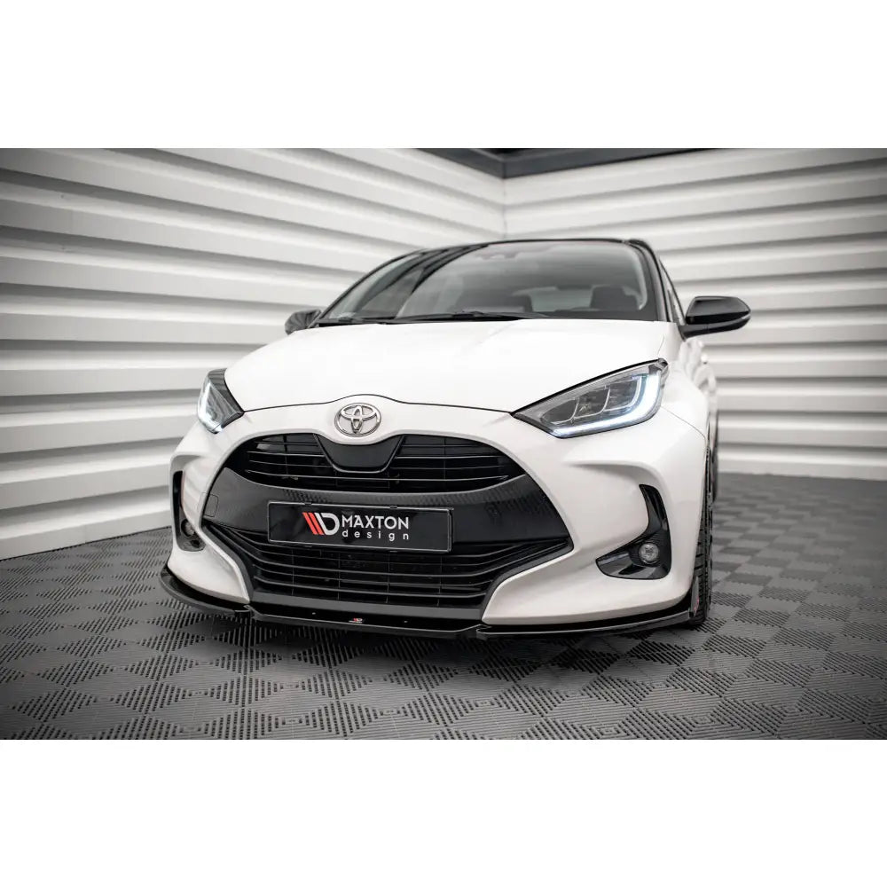 Front splitter på Toyota Yaris Mk4 V1 med flaps, hvit bil med svart grill og LED-frontlys.
