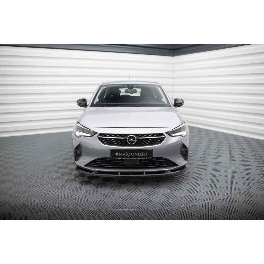 Spoiler foran på Opel Corsa F V1, sølvfarget bil med svart grill, fotografert innendørs.