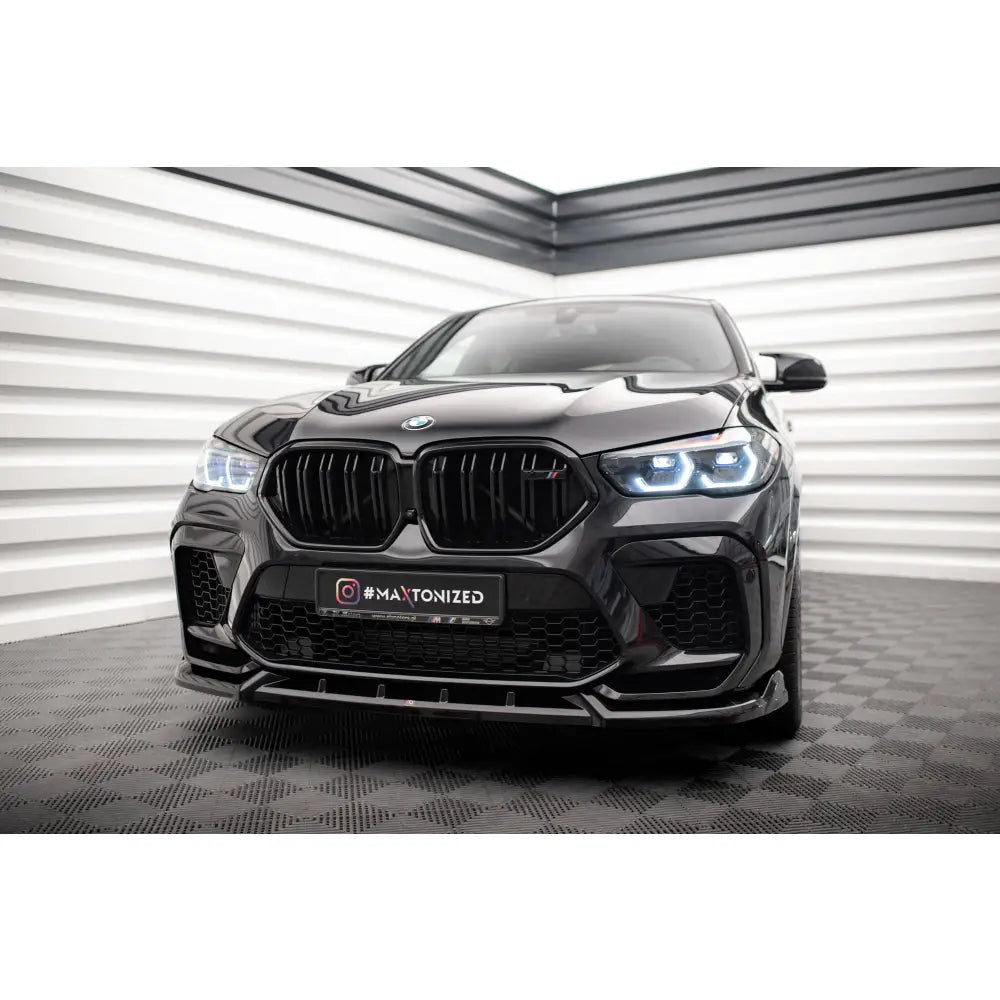 Frontleppe på BMW X6 M F96 V2 med sort grill og LED-frontlykter, sett forfra i lyst rom.