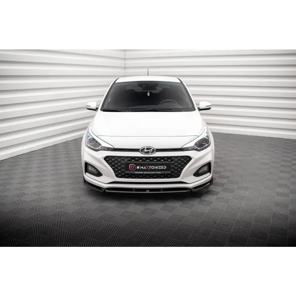 Spoiler på Hyundai I20 Mk2 Facelift V2 sett forfra, hvit bil med sort grill i lyst rom.