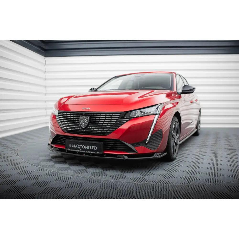 Frontleppe på Peugeot 308 Mk3 V2 med sorte felger, markant grill og LED-lys, sett forfra innendørs.