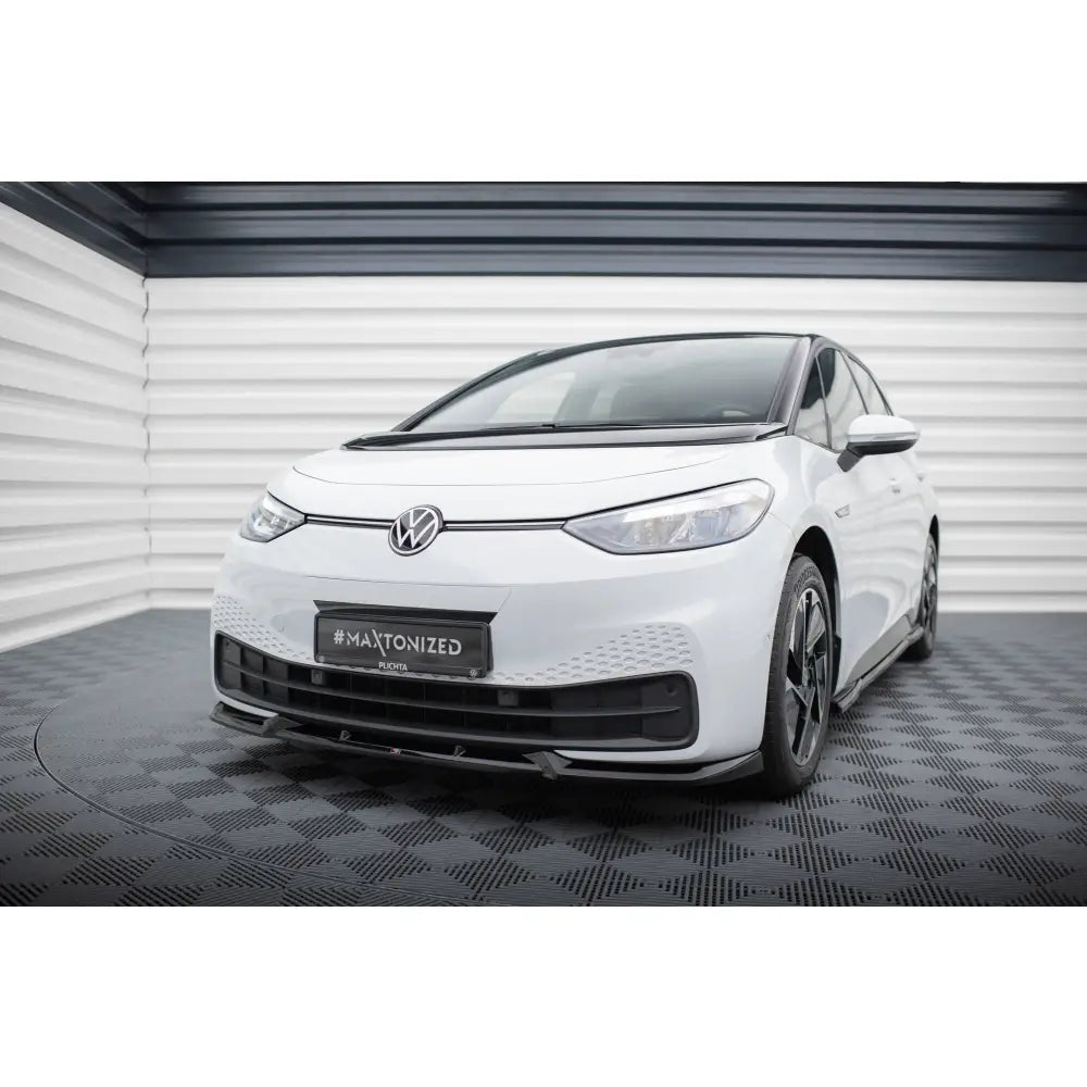 Frontleppe på Volkswagen ID3 Mk1 V2 med sorte detaljer, sett skrått forfra mot stripete bakgrunn.