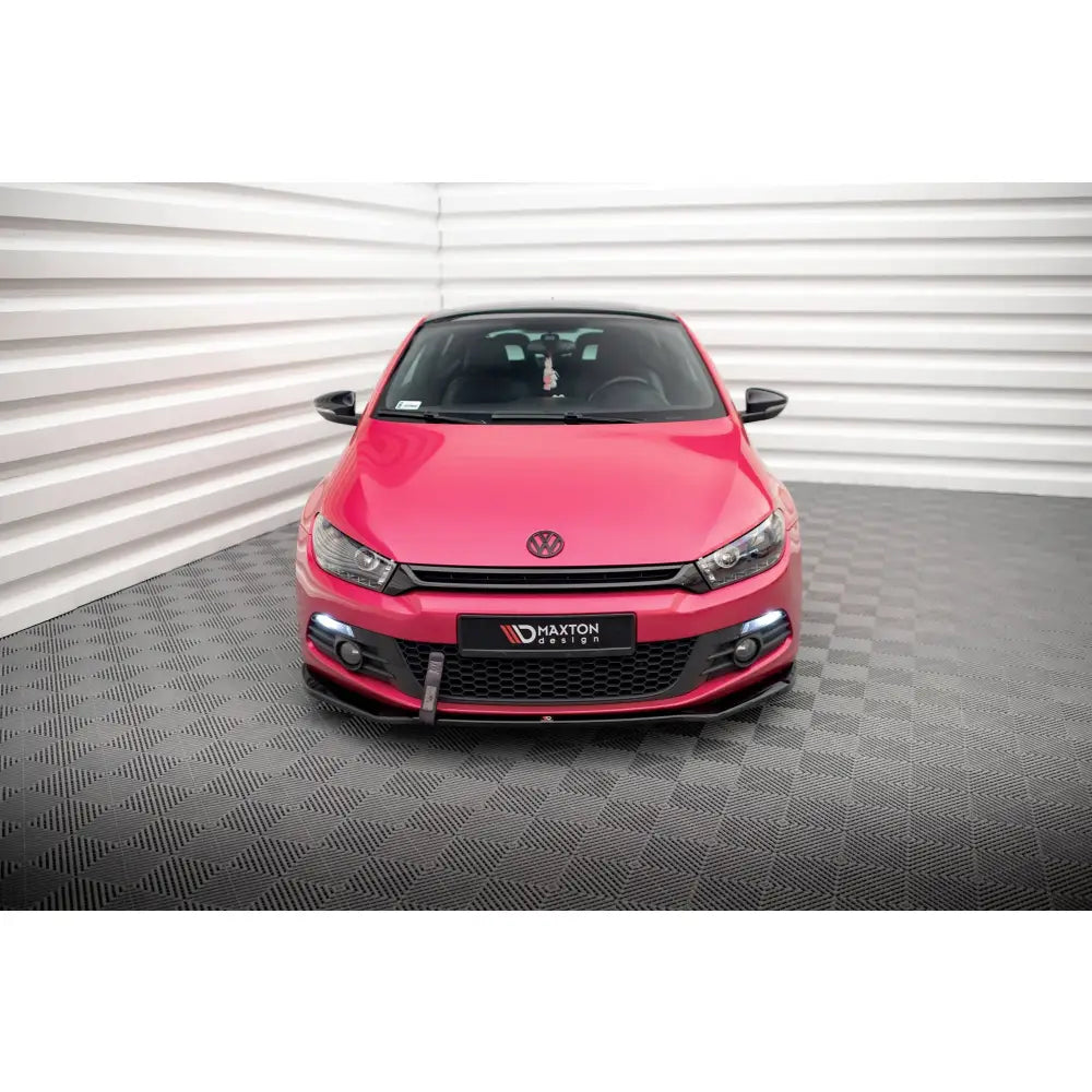 Spoiler på Volkswagen Scirocco Mk3 V2 i rødt, sett forfra med svarte detaljer på grill og sidespeil.