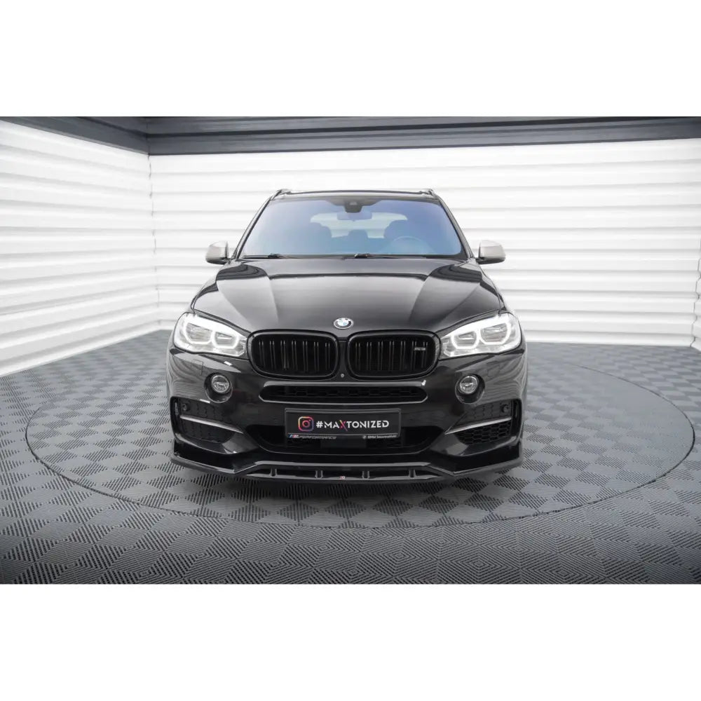 Spoiler på BMW X5 M-Pack F15, svart SUV sett forfra med LED-lykter og sort grill i lyst studio.