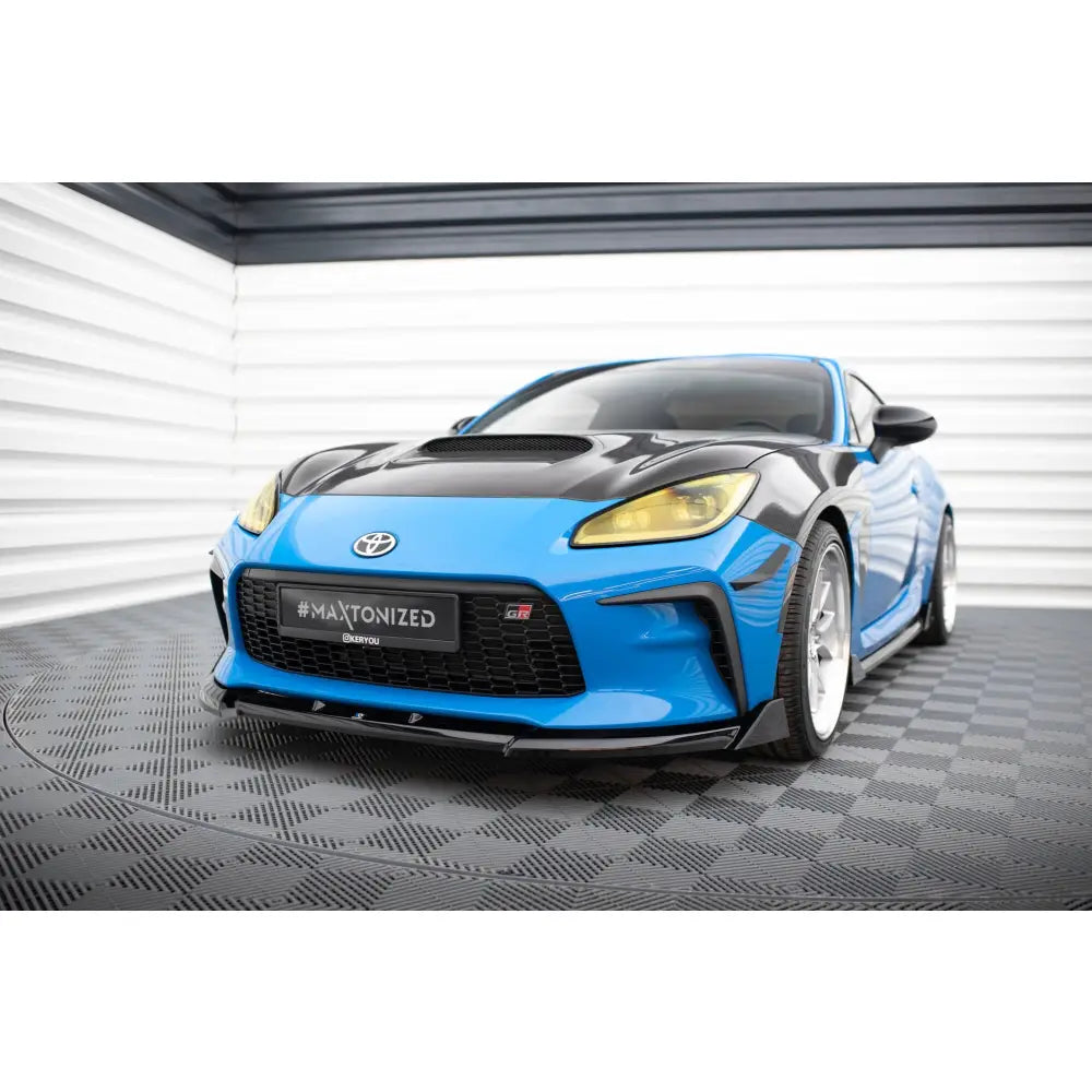 Frontleppe på Toyota GR86 Mk1 V3 sportsbil, blå og svart, med stor frontgrill og gule frontlys.