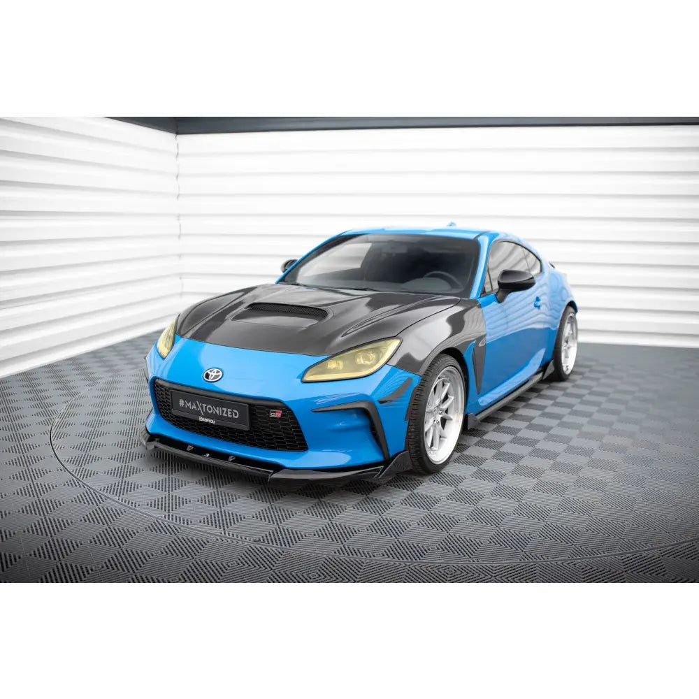 Front lip på Toyota GR86 Mk1 V3 sportsbil med blå og sort karosseri, gule lykter og hvite felger.