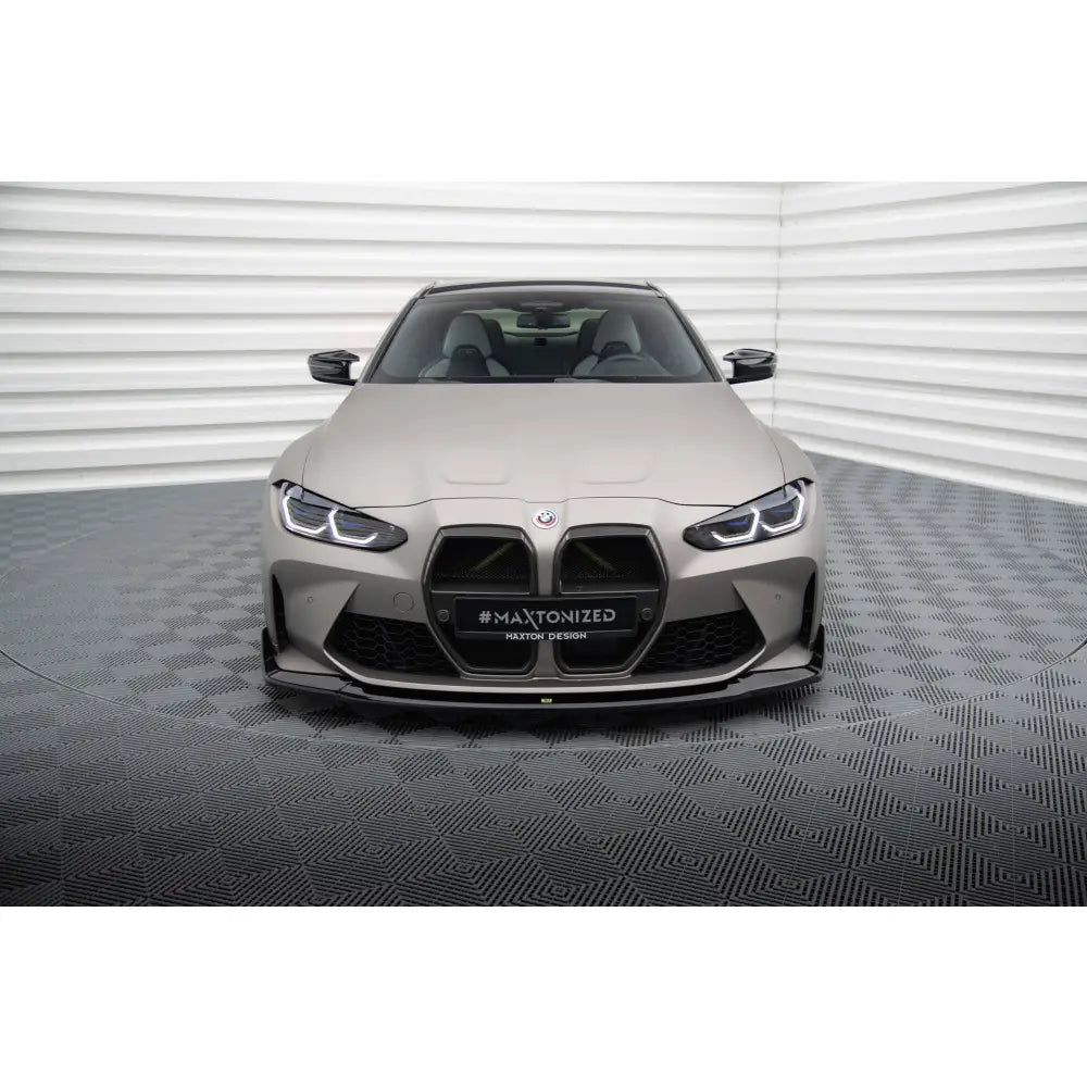 Front splitter på BMW M4 G82 med sorte luftinntak og markante LED-frontlys i lyst rom.